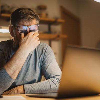Mature men at home during pandemic isolation reading something on laptop